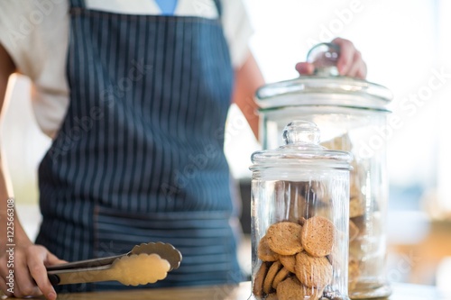 Fotobehang Waitress holding jar and tong in café
