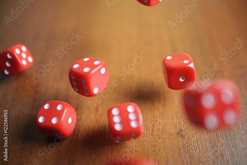 Several rolling red dice fall on a table