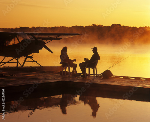 a couple relaxes on a float plane dock, Manitoba, Canada