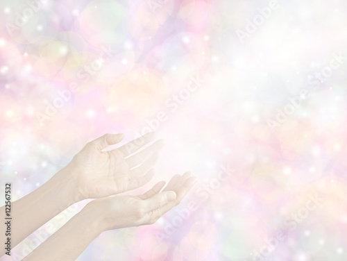 Sending Divine healing energy - female hands held out with a stream of white light on a soft pale pastel bokeh multicolored background with copy space all around 