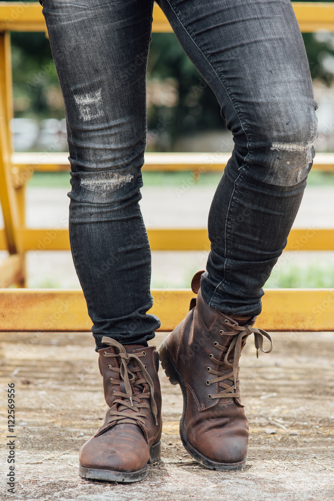 Men fashion, man's legs in black jeans and brown leather boots.