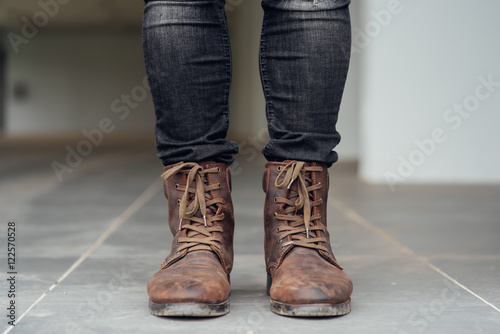 Close up view on man's legs in black jeans and brown leather boots.Toned picture. © siwarit01