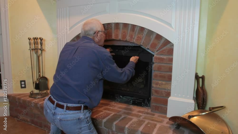 Man cleaning and maintaining home gas fireplace.