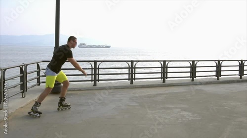 Sporty man roller skating on waterfront and falling while trying to jump HD photo