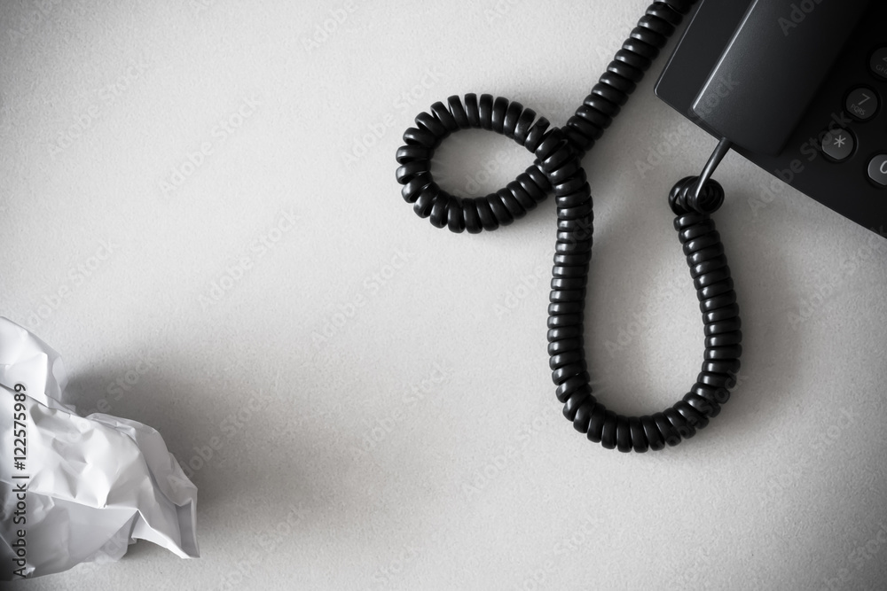 black land line telephone and white crumpled paper on textured white granite surface black land line telephone and white crumpled paper on textured white granite surface
