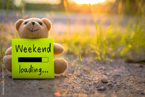 Happy Weekend on sticky note with teddy bear on nature background photo