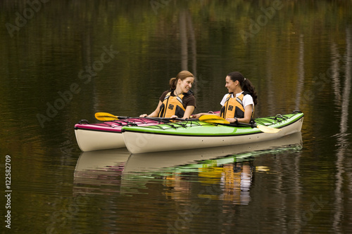 Two young women kayaking on Oxtongue Lake in autumn, Mukoka, Ontario, Canada.
