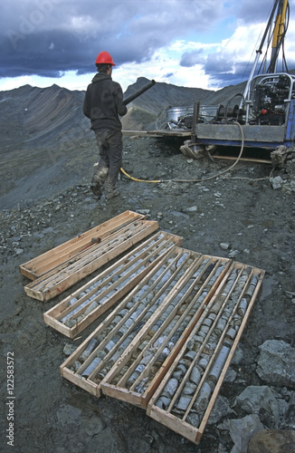 Drill rig operator taking drill pipe back to rig, Yukon Territory, Canada