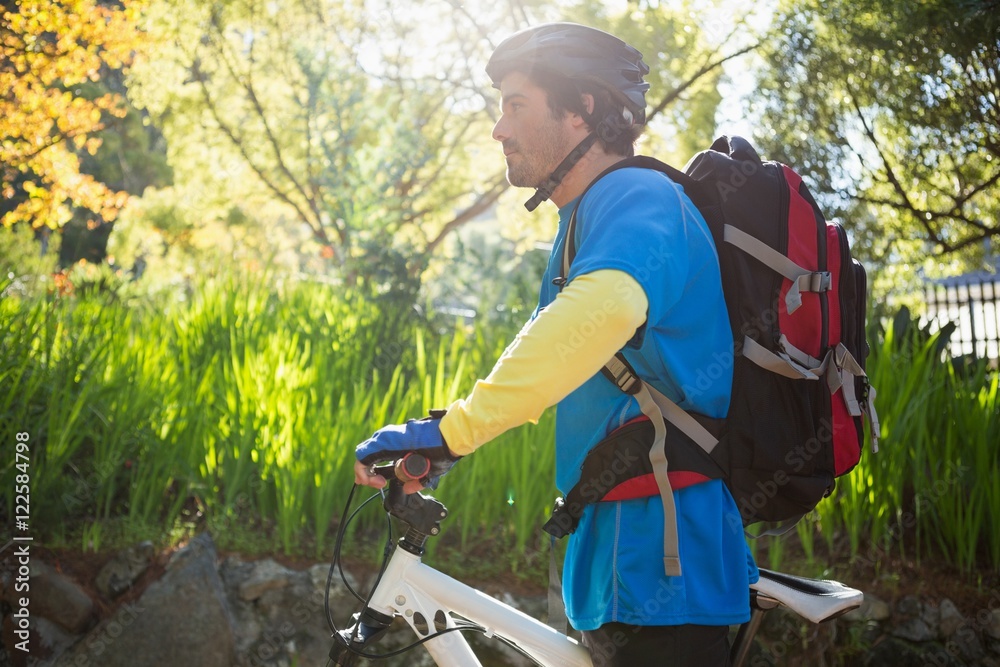 Male mountain biker with bicycle in the forest