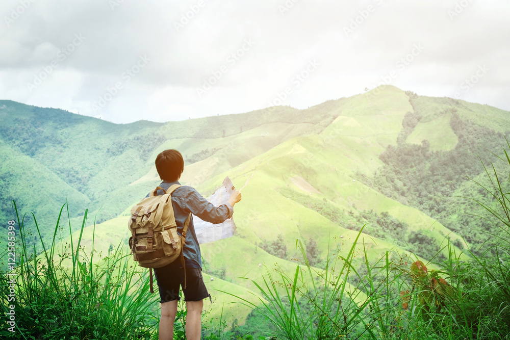 hipster traveler man holding map at mountains with amazing view