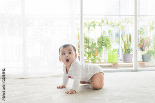 Little pretty baby girl crawling on the floor at home