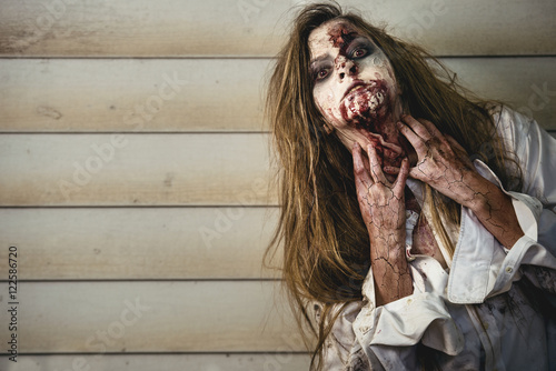 Quadro su tela Scary and bloody zombie woman at the backyard. Halloween concept