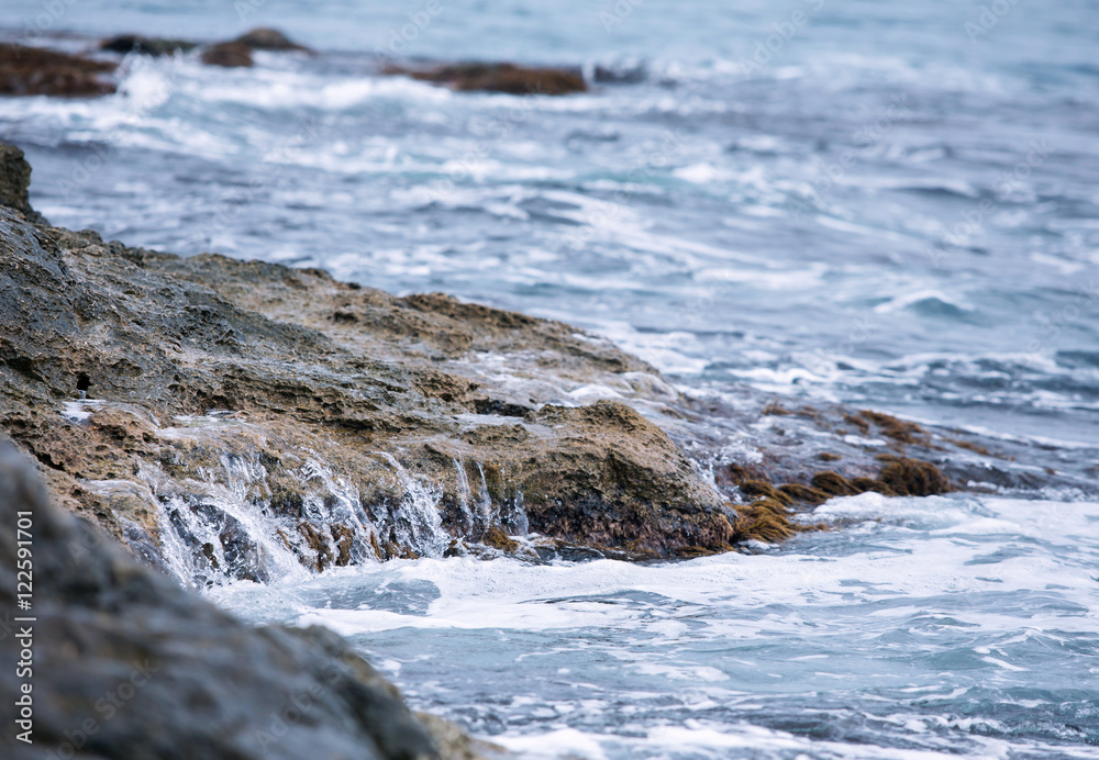 Deep dark blue sea waves breaking on a rocks forming a sea foam.