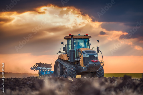 Canvas Print Farmer in tractor preparing land with cultivator
