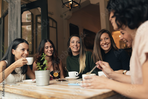 Smiling women having coffee and chatting photo