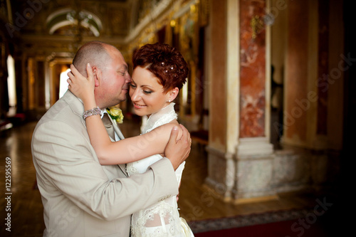 Cheerful groom with hug seductive bride tender while they pose i