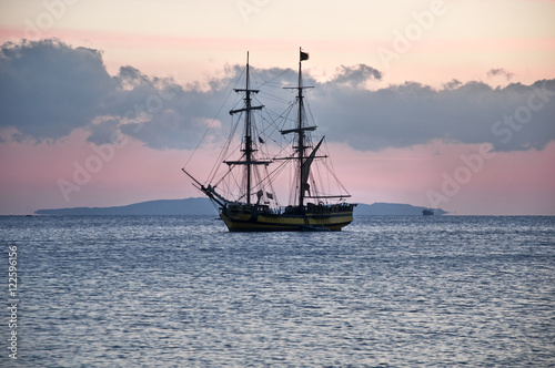 sailing ship at anchor, a calm sea and cloudless sky
