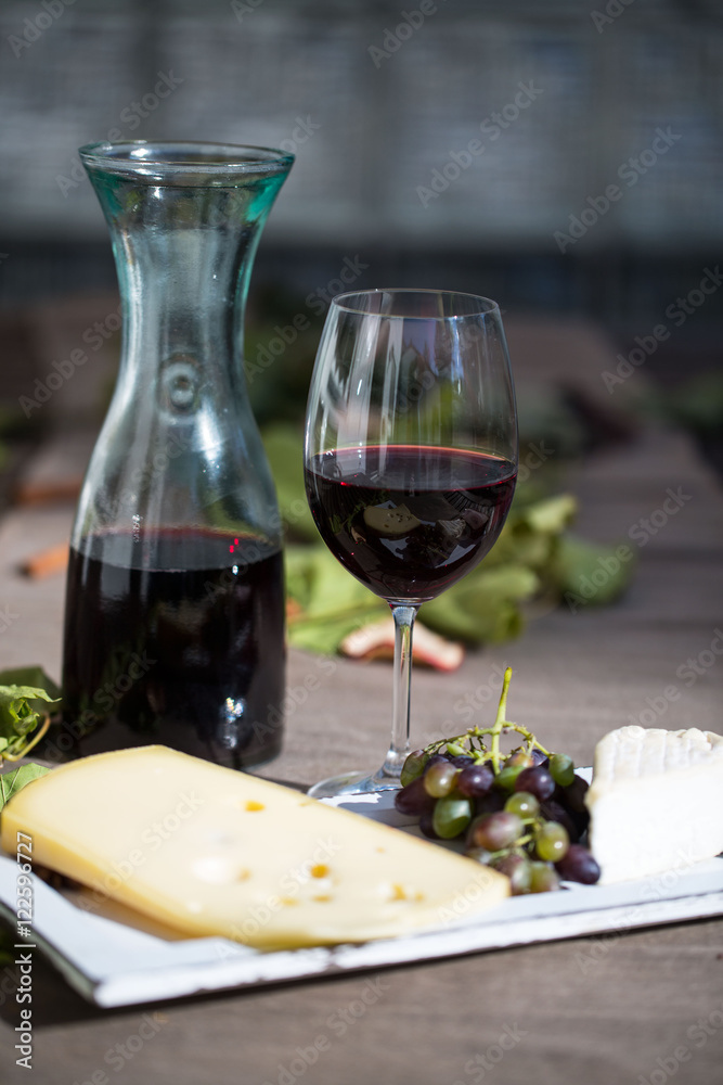 Weinkaraffe mit einem Glas Rotwein und Käse