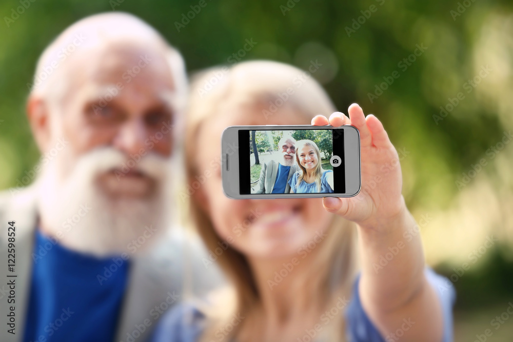 Grandfather and granddaughter taking picture on blurred background