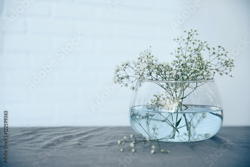 Glass vase with gypsophila twigs on table