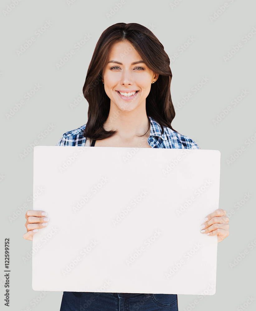 Happy young woman holding blank white banner isolated on gray Happy young woman holding blank white banner isolated on gray