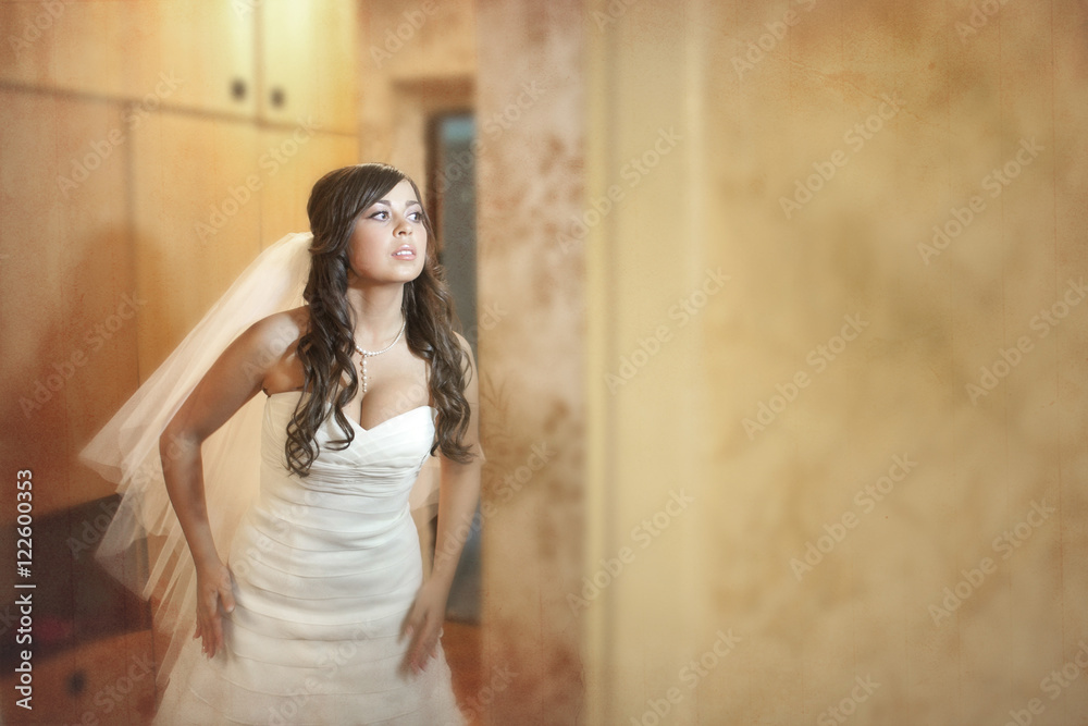 Bride bends ahead while posing in the room Bride bends ahead while posing in the room