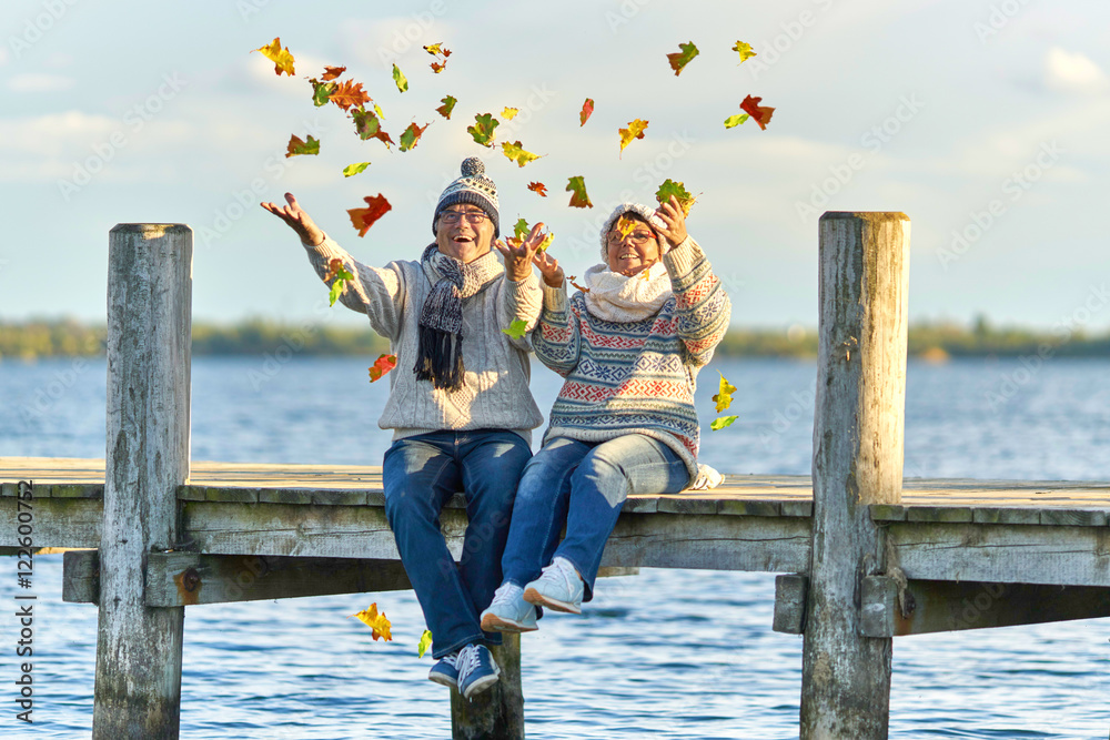 Wunschmotiv: Seniorenpaar wirft buntes Laub in die Luft, Herbsttag am See #122600752