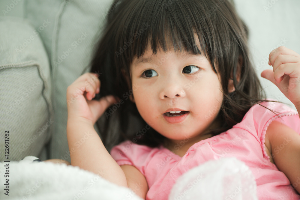 child and happiness concept - smiling little asian girl on sofa at home child and happiness concept - smiling little asian girl on sofa at home