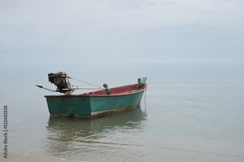 Traditional wooden fishing boat floating on the peace surface wave of the seas,in the afternoon against the blue waters,selective focus,minimalism
