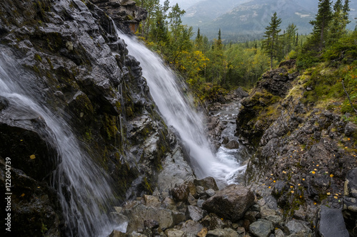 Gloomy weather. View at waterfall in mountain with foliage and woods over rocks colored with first autumn colors  Russia  Hibiny