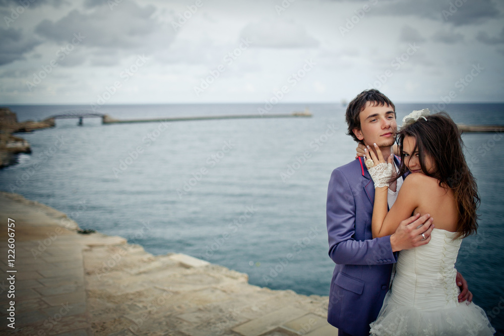Groom in blue suit looks proud while hugging gorgeous bride on t Groom in blue suit looks proud while hugging gorgeous bride on t