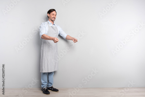 Delighted man making cooking gesture on a grey background photo