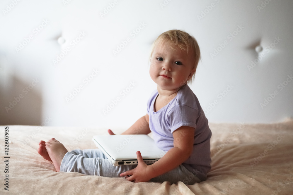 blond toddler playing with pc laptop at home, indoors. blond toddler playing with pc laptop at home, indoors.