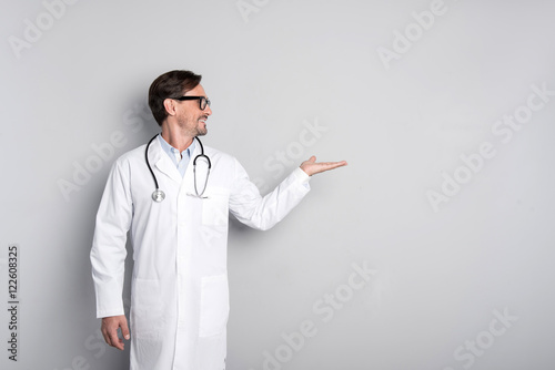 Canvas Print Smiling doctor with stethoscope gesturing