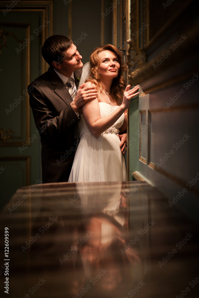 Groom admires bride while she leans to the wall with lamp