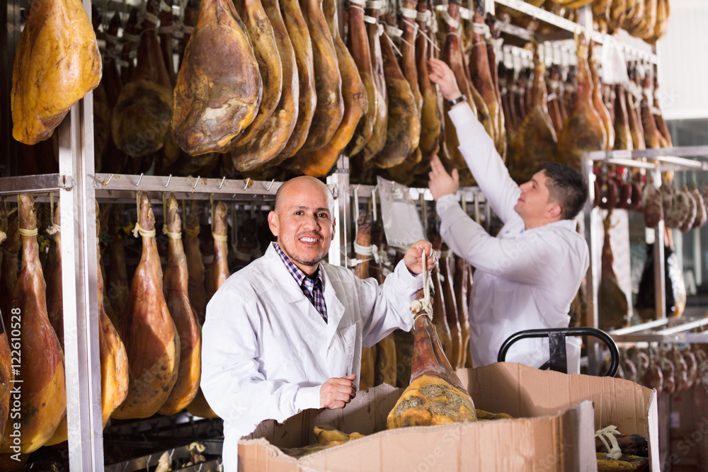 Ordinary smiling  technologists checking joints of iberico jamon