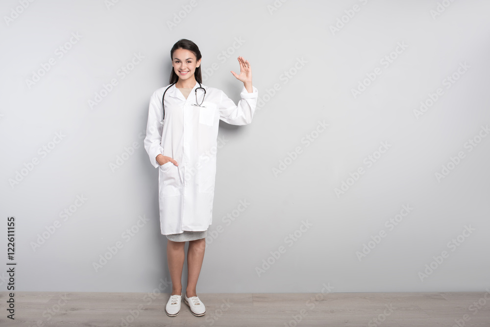 Cheerful professional doctor standing on grey background Cheerful professional doctor standing on grey background