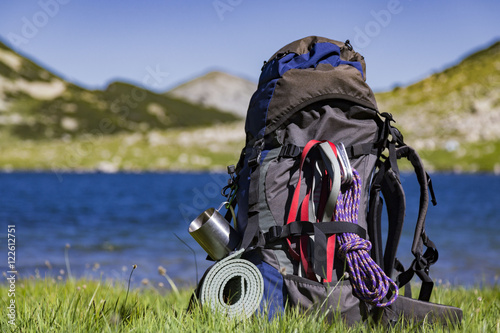 Hiking backpack camping and mountain exploring tourist equipment outdoor on grunge wall. Adventure, summer, tourism active lifestyle