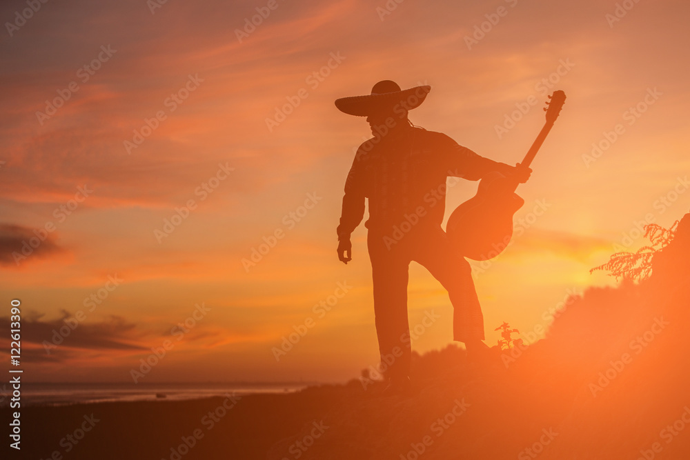 Mexican musician mariachi on the coast. Silhouette at sunset.