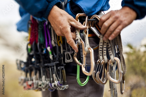 Close up of man adjusting climbing carabiners