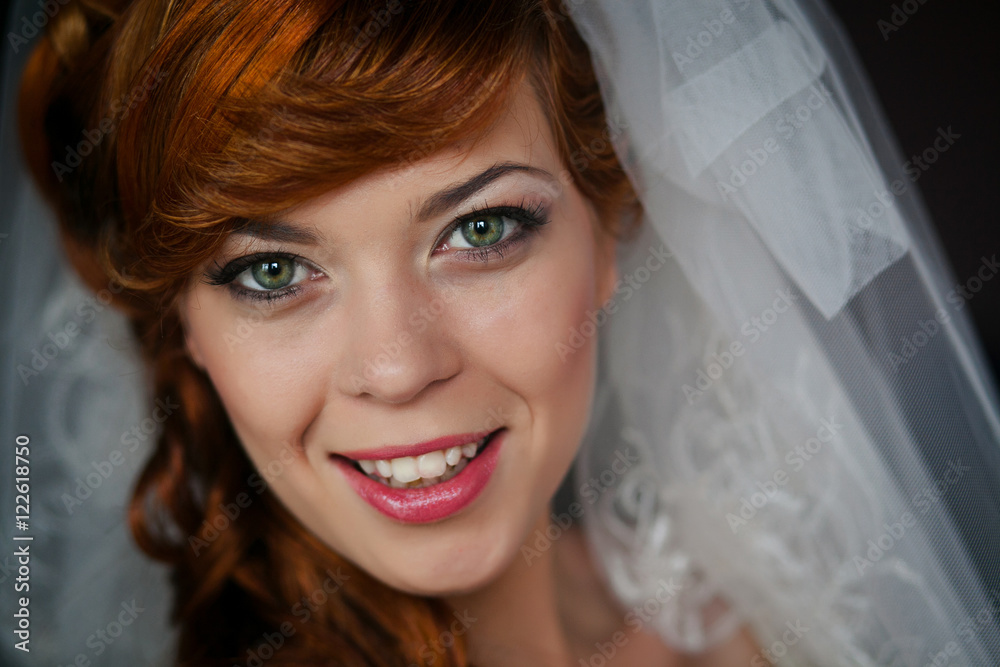 Green-eyed bride with red hair smiles tender