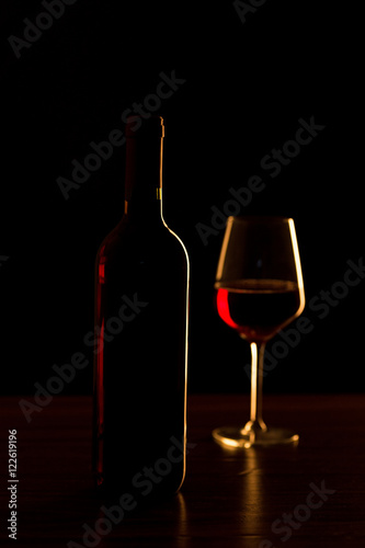 Red wine bottle with glass on black background - silhouette