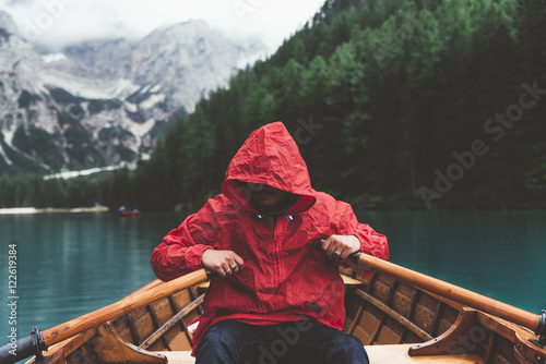 Man with red raincoat rowin...