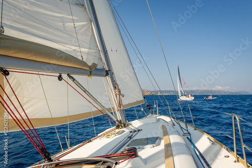 Sailing boat going fast on she's sails, view from the cockpit to bow. © AlexanderNikiforov