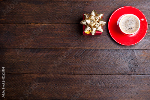 Coffee cup and present on old dark wooden background. Gift box for Valentines day. Christmas background. Top view. Copy space