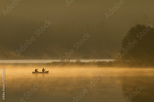 Two men canoeing on Oxtongue Lake at sunrise, Canada