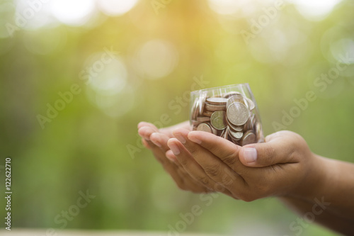 Hand with coins on bokeh background .save money concept