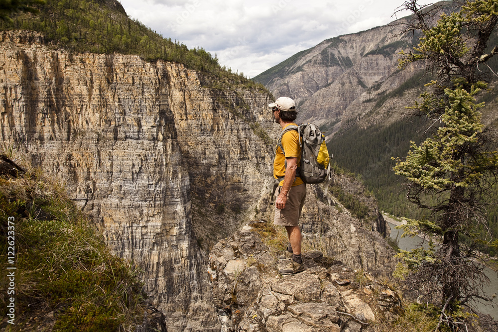 Man on cliff face above Nahanni River near 'The Pulpit' rock formation, Nahanni National Park Preserve, NWT, Canada. Man on cliff face above Nahanni River near 'The Pulpit' rock formation, Nahanni National Park Preserve, NWT, Canada.