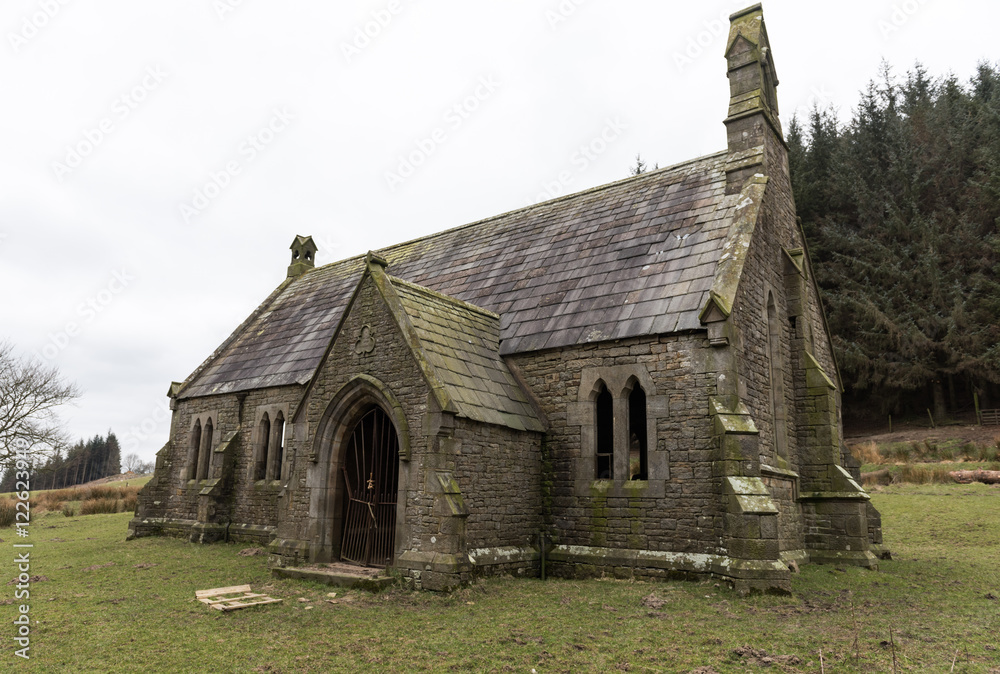 An creepy old abandoned christian church, on a gloomy overcast day, covered in moss, deep in the english countryside.