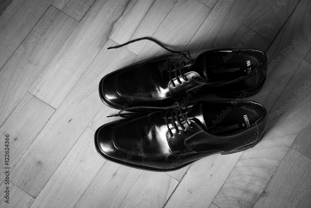Black and white photo of lacquer shoes standing on the wooden fl